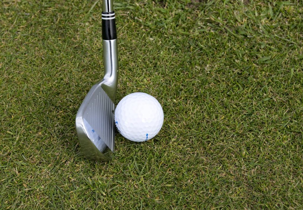 Golf club and ball on grass showcasing a leisure sport scene outdoors.